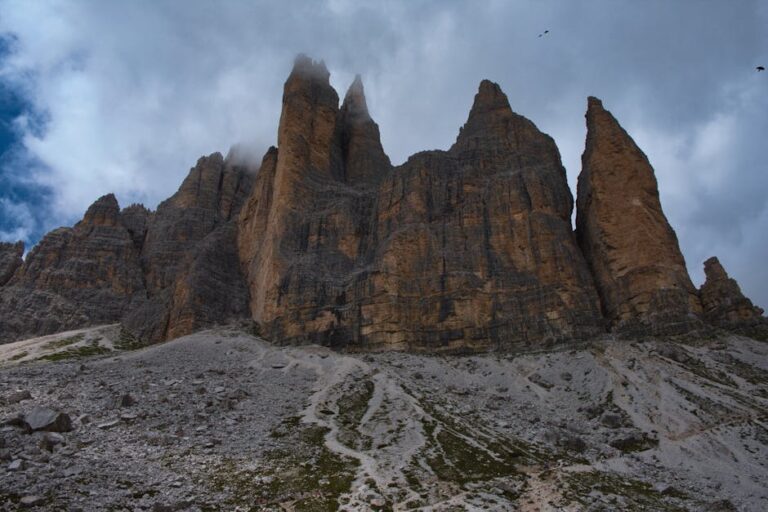 Stunning view of Tre Cime di Lavaredo in the Italian Dolomites with dramatic clouds overhead.
