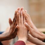 Close-up of diverse group hands high-fiving symbolizing teamwork and unity.