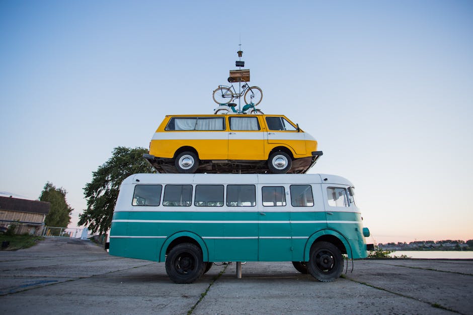 Creative outdoor sculpture featuring a van stacked on a bus with a bicycle on top.
