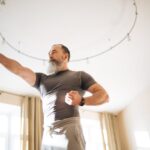 Elderly man performing yoga indoors to stay healthy. Emphasis on active lifestyle and wellness.