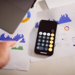 Business analytics setup with calculator, graphs, and laptop, showcasing financial insights.