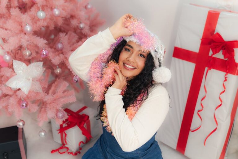 Portrait of a joyful woman with Christmas decorations, pink tree, and gifts.