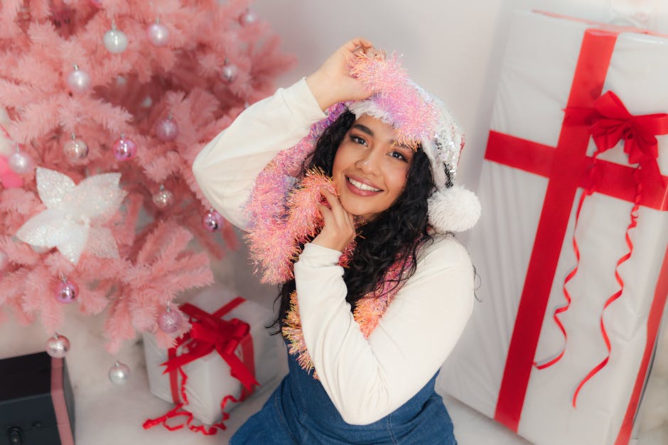Portrait of a joyful woman with Christmas decorations, pink tree, and gifts.