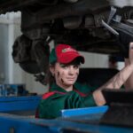 Female mechanic maintaining a car in an auto repair shop, showcasing skill and concentration.