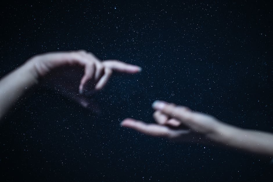 Artistic depiction of two hands almost touching against a backdrop of a starry night sky.