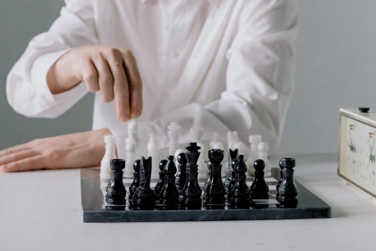 Close-up of a person's hand making a chess move indoors, highlighting strategy.