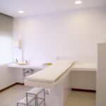 Minimalist white clinic room with examination table and furniture.