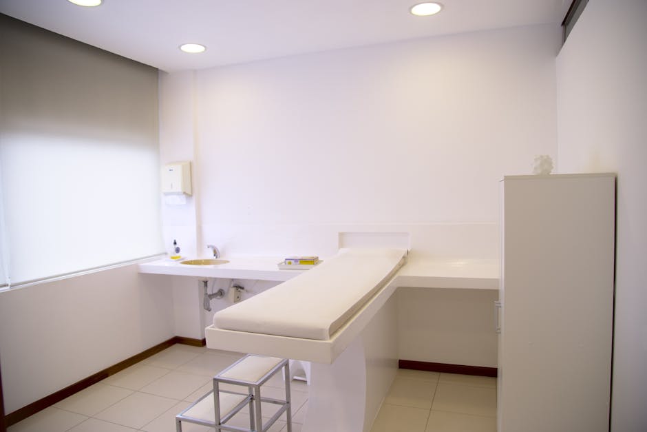 Minimalist white clinic room with examination table and furniture.
