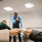 Focused hands exchanging paper in a classroom environment indicating discreet communication.