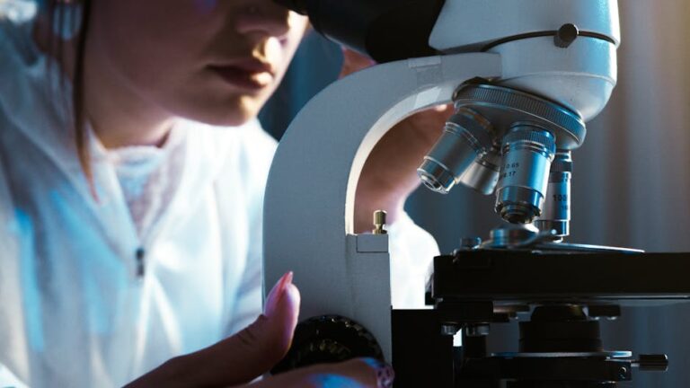 Scientist examining samples with a microscope in a laboratory setting.