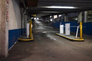 Entrance ramp of an underground parking garage with barriers and dim lighting, depicting urban infrastructure.