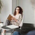 Businesswoman sitting in a modern office with a notebook, exuding professionalism and confidence.