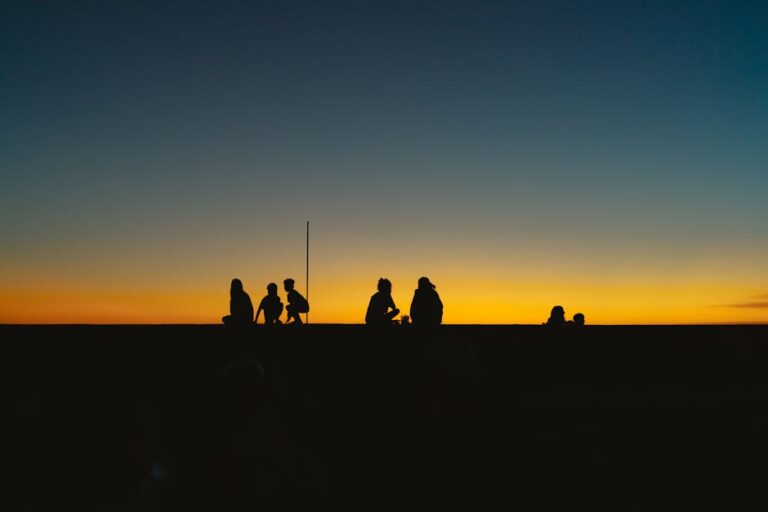 Silhouettes of people against a vibrant sunset on a beach in Bình Thuận, Vietnam.
