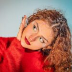 A close-up portrait of a woman in festive makeup and red sweater, exuding holiday joy.
