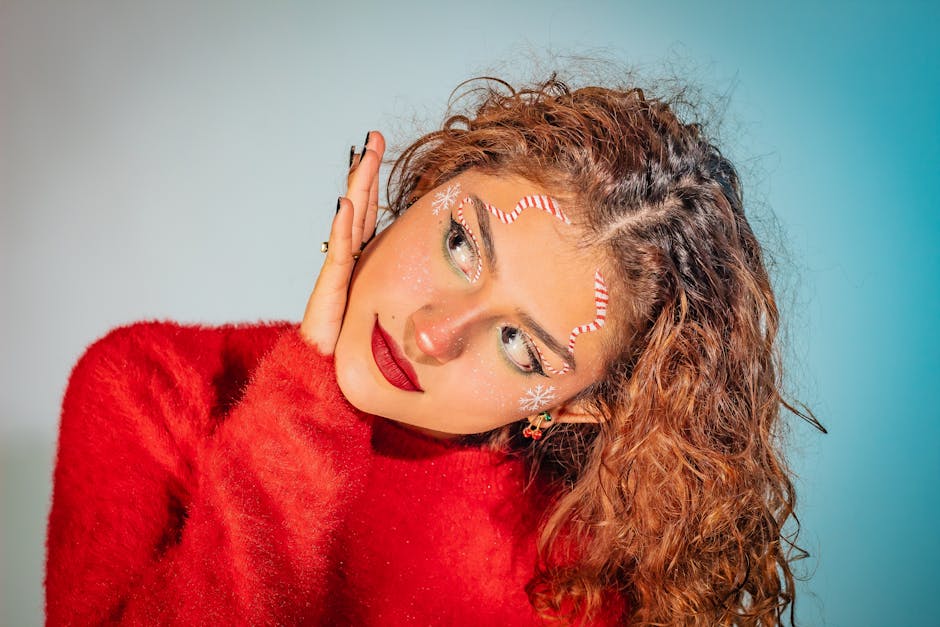 A close-up portrait of a woman in festive makeup and red sweater, exuding holiday joy.