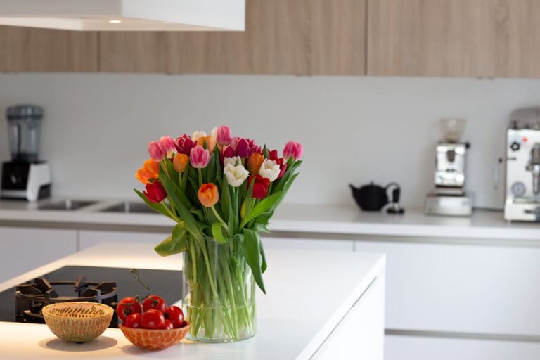 Bright tulips in a vase add a pop of color to a sleek modern kitchen interior.
