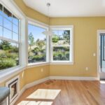 Spacious sunlit room with wooden floors and garden views, creating a serene indoor space.