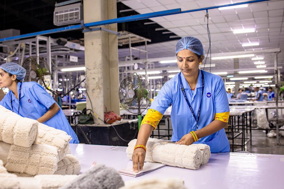 Indian textile worker organizing fabric rolls in a factory setting.