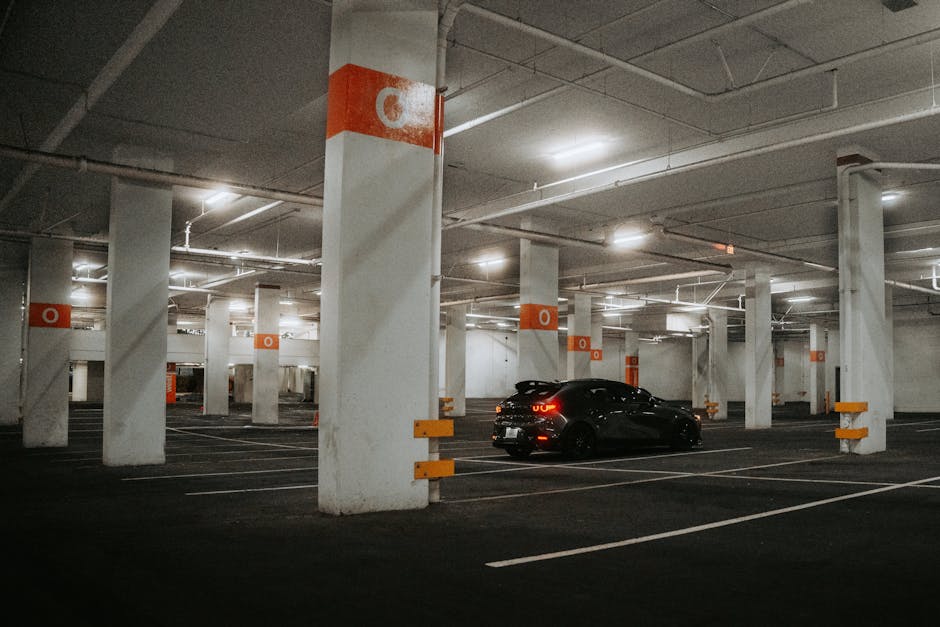 A dimly lit underground parking garage with a single car parked, creating a moody urban atmosphere.