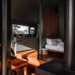 A modern cabin interior featuring wooden floors, cozy furniture, and abundant natural light.