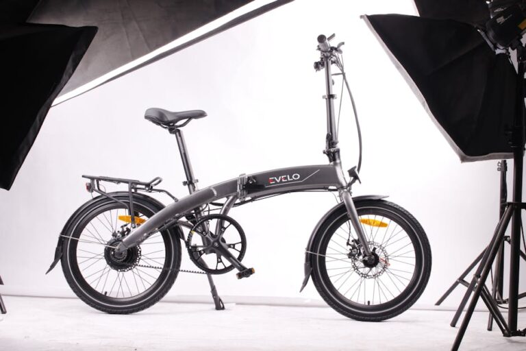 Modern foldable black electric bicycle displayed in a studio environment with white background and lighting equipment.
