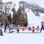 Children learning to ski during a winter lesson at a snow-covered mountain resort.