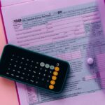 Tax form 1040 with a calculator on a pink background, highlighting finance and accounting themes.
