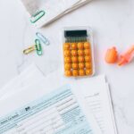 A flat lay image of tax forms, calculator, and office supplies on a desk.