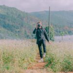 A photographer captures the scenic beauty of a rural flower field in natural daylight.