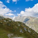 Breathtaking view of the Swiss Alps with lush greenery and rugged peaks under a deep blue sky.