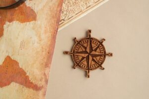 Wooden compass rose and vintage map on beige background, perfect for travel themes.