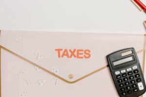 Flat lay of a calculator and folder labeled 'Taxes' for finance and accounting.